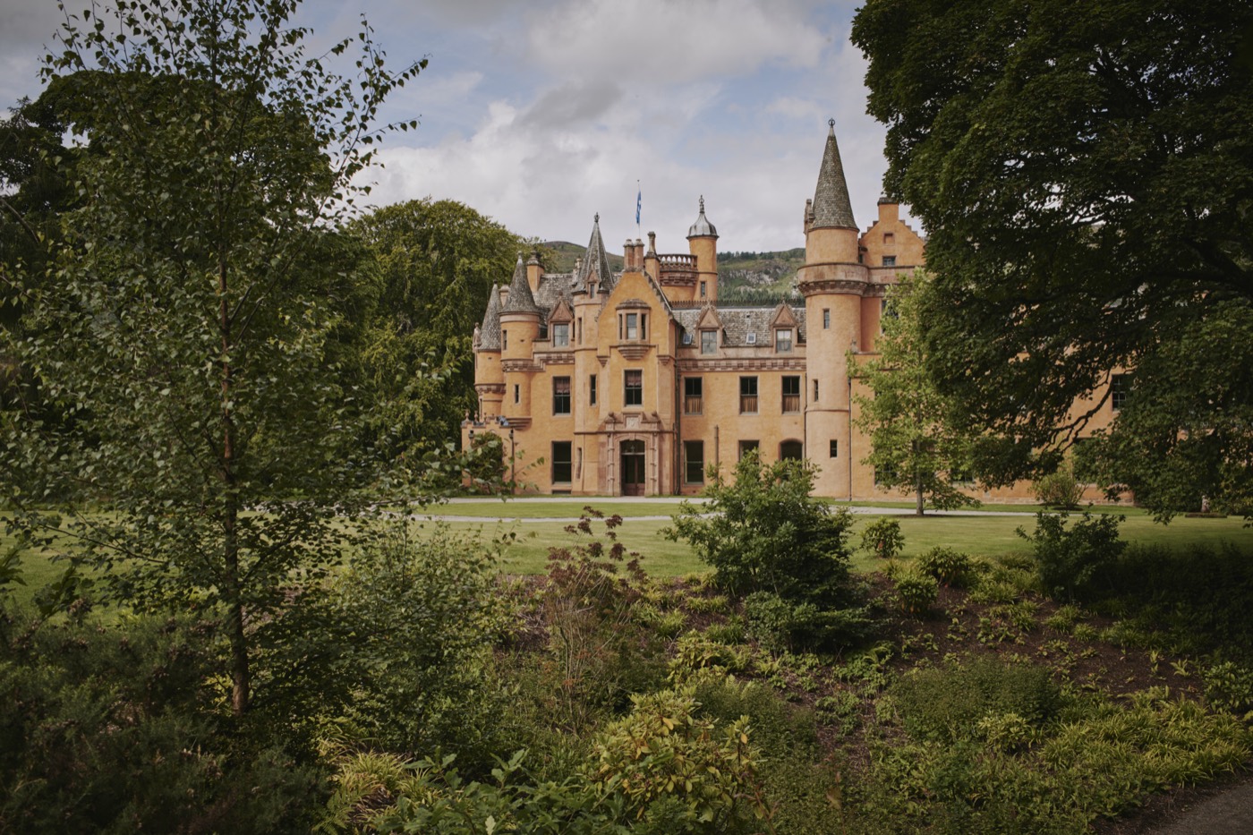 Scottish baronial castle estate in honey-coloured sandstone framed by woodland · Scotland